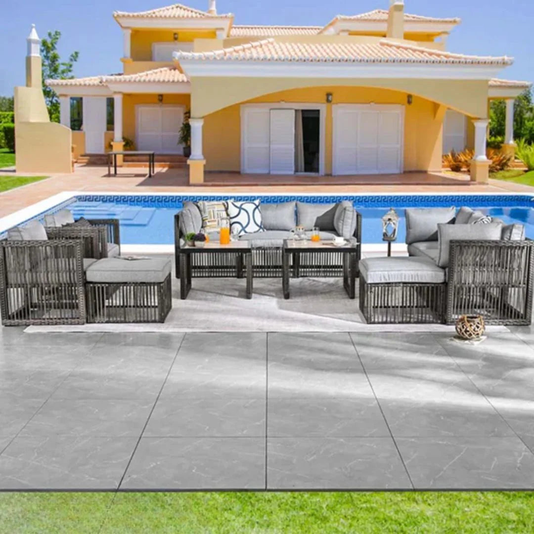 Outdoor patio furniture set by a pool with a house in the background