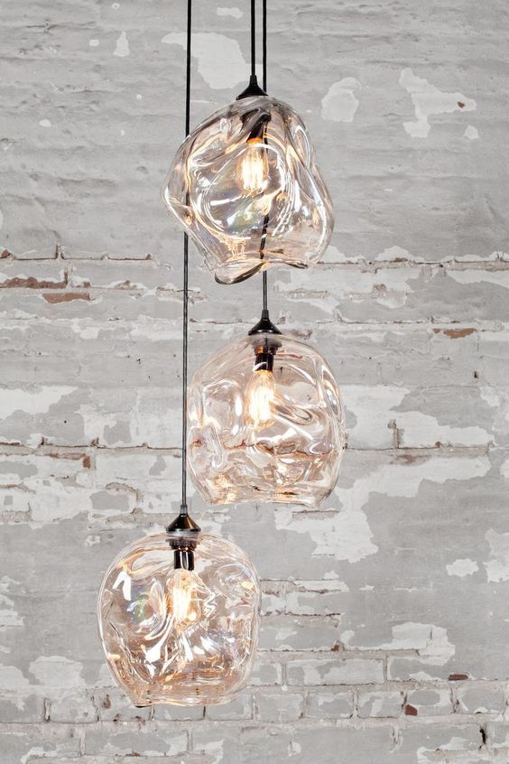 Three glass pendant lights hang against a textured gray wall.