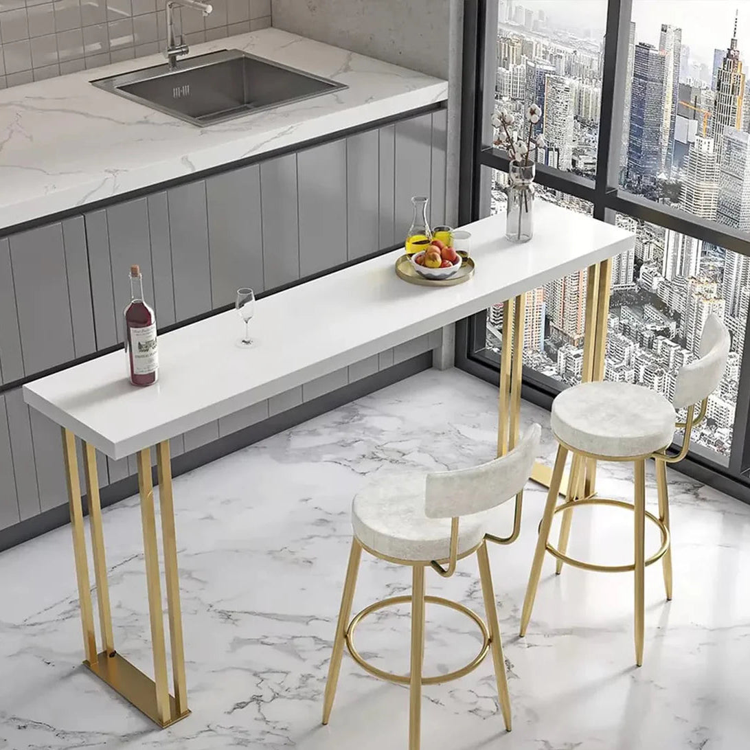 Modern kitchen bar with white countertop, gold legs, and stools in a cityscape view.