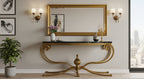 Gold console table with marble top in a room with a large mirror and wall sconces.