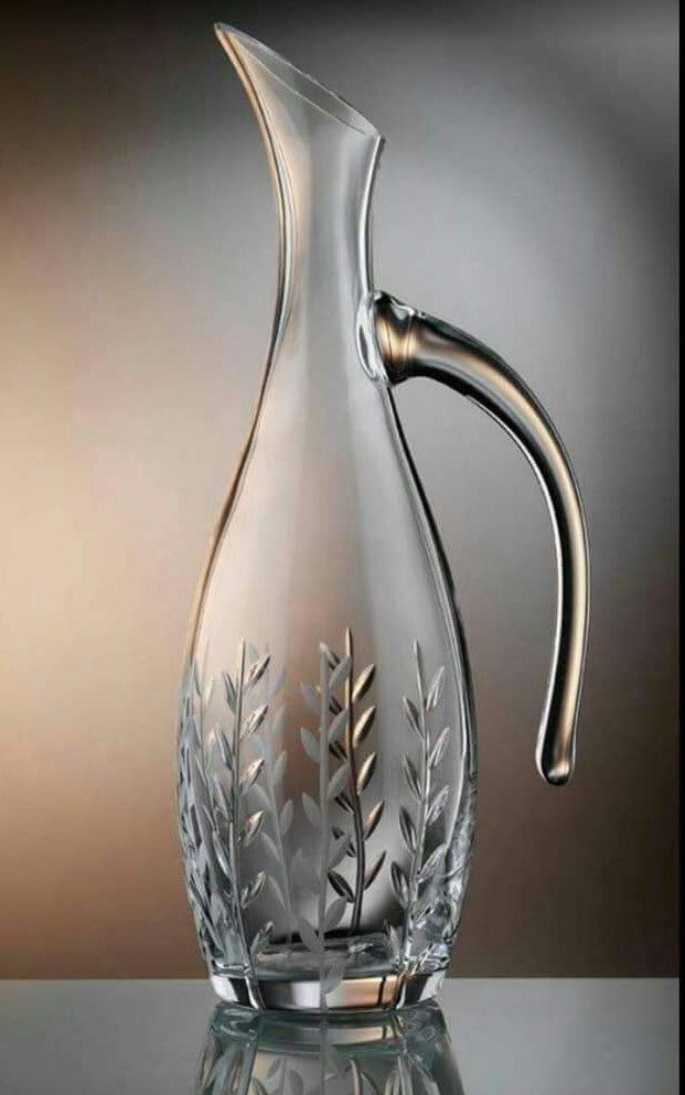Glass carafe with metal handle on a reflective surface
