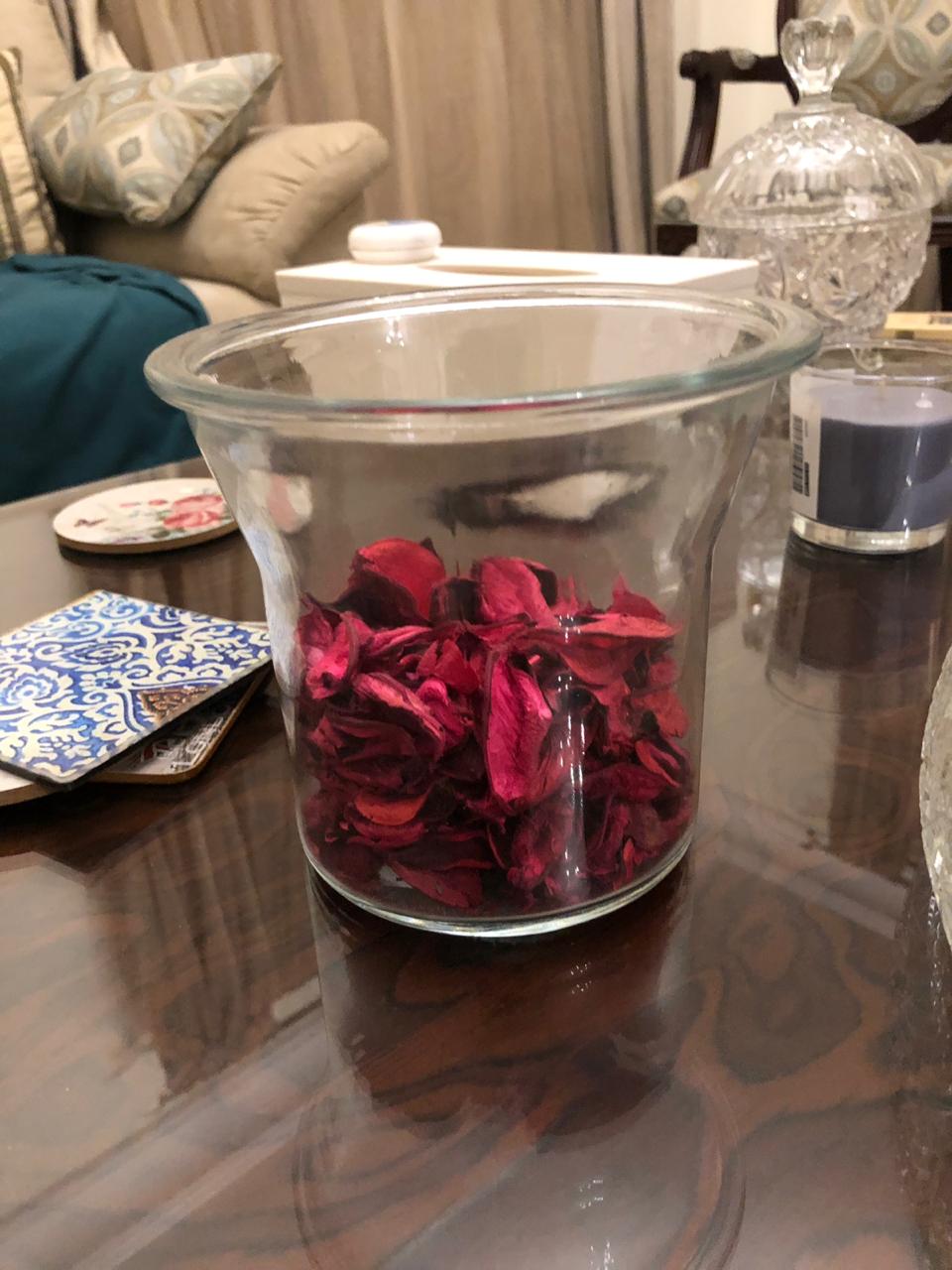 Glass jar with red flowers on a reflective surface
