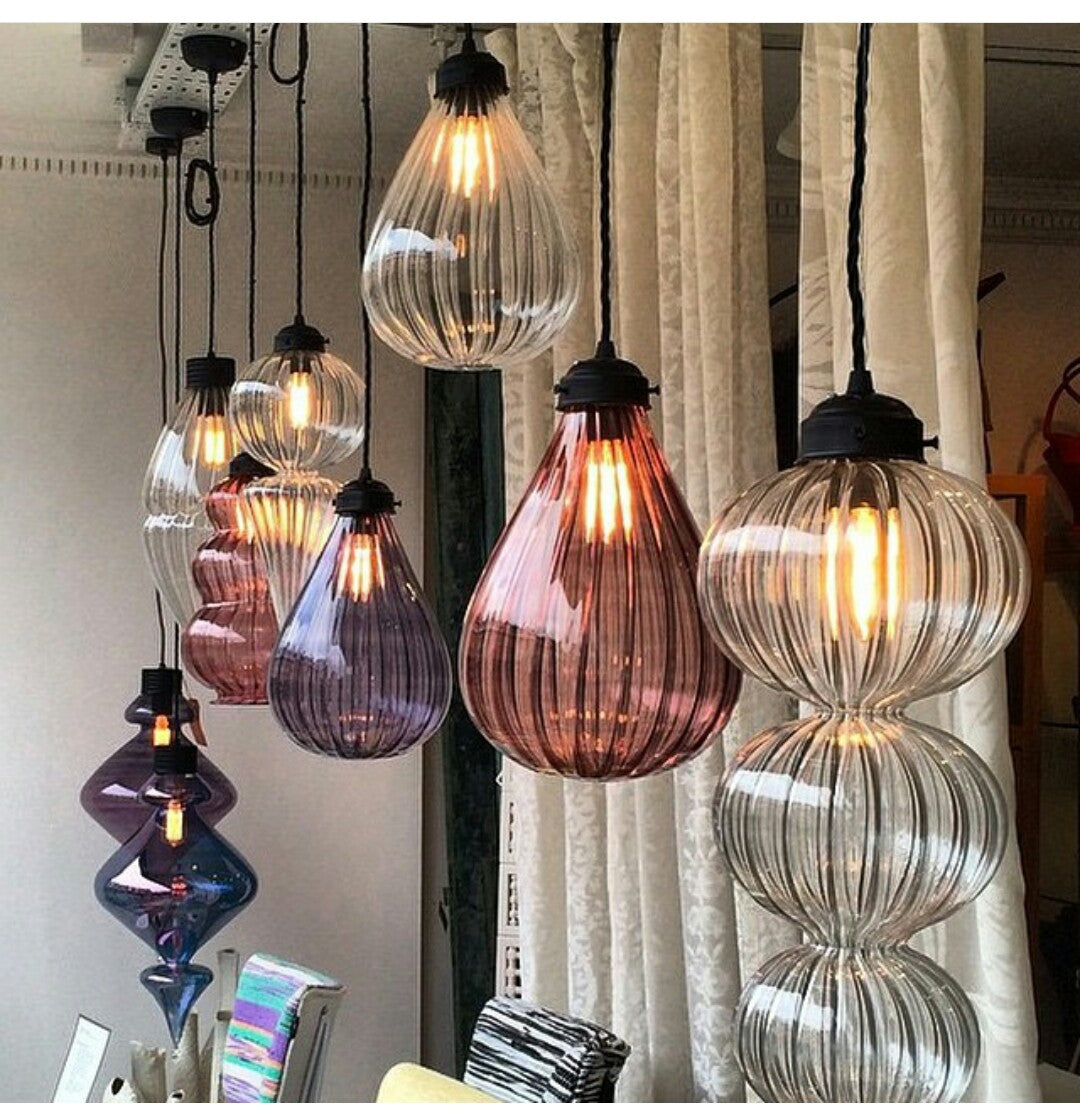 Collection of colorful glass pendant lights hanging in a room.
