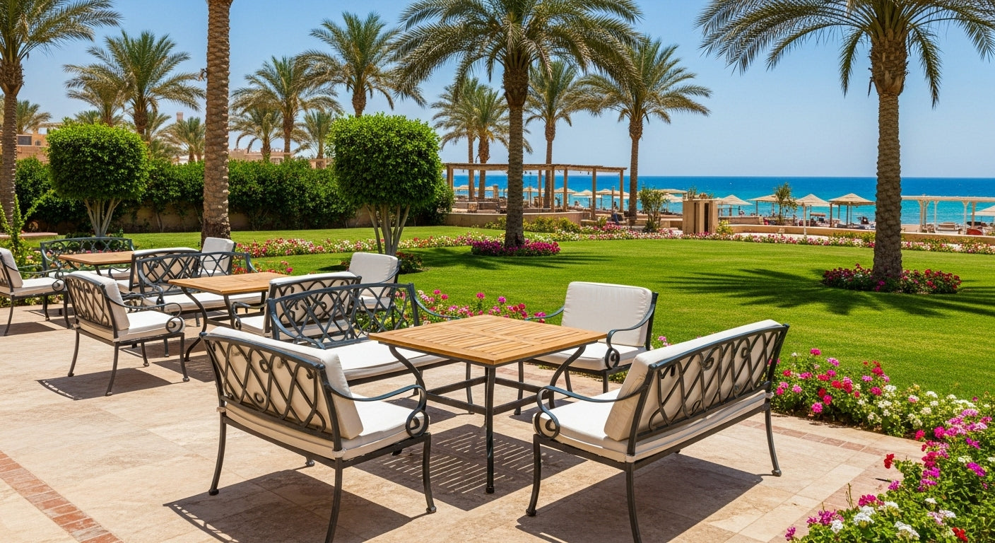 Outdoor seating area with tables and chairs on a patio near a beach with palm trees and ocean view.
