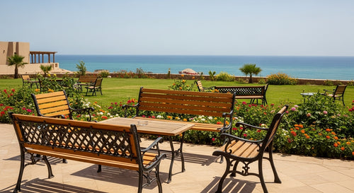 Outdoor seating area with wooden benches and tables by a scenic ocean view.